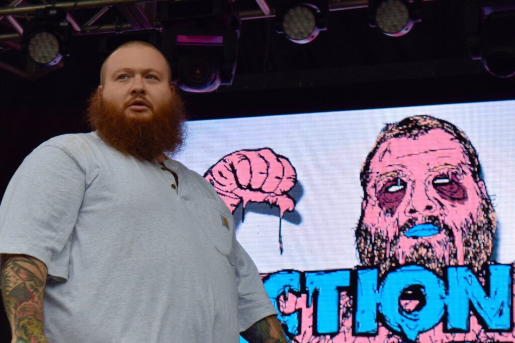 Joe Rogan Stem Cell Action Bronson performs on stage in June 2016. He's bald with a long reddish beard wearing a gray t-shirt.