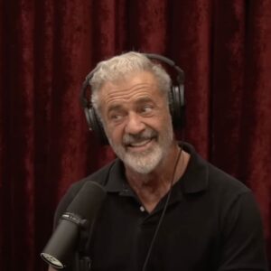 Joe Rogan Talks Stem Cell Therapy Mel Gibson in front of a red curtain being interviewed by Joe Rogan